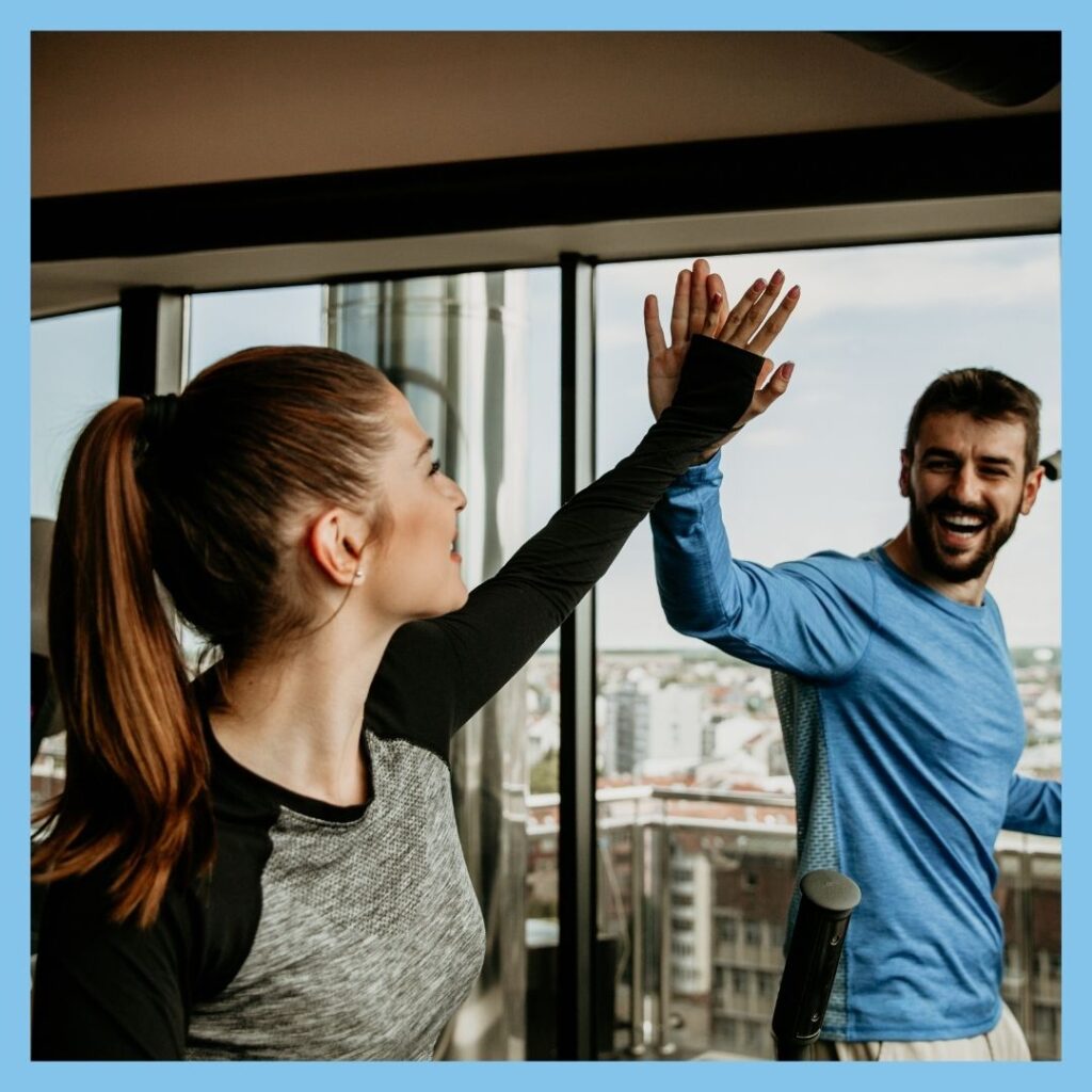 man and woman high fiving on treadmill